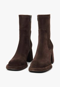 Hnědé semišové kotníkové boty se čtveratou špičkou, masivním podpatkem a bočním zipem. Hladká textura s tónovými švy.