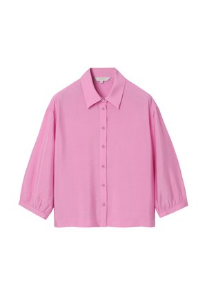 Rozā pogājamā krekla izgatavots no gludas auduma, ar izplatu apkakli un īsām uzpūstām piedurknēm. Aizmugurē ir taisni nogriezta apakša.