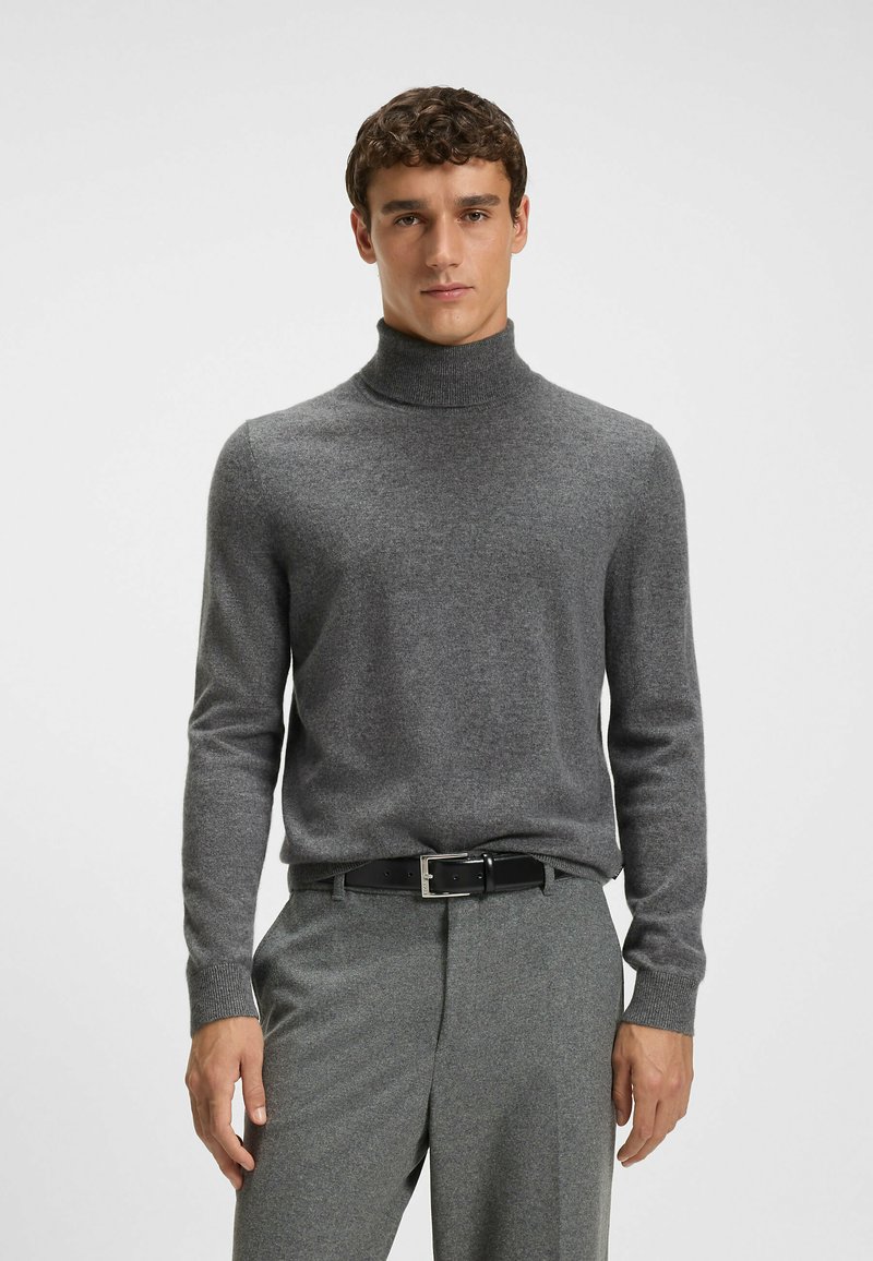 Szary sweter z golfem wykonany z miękkiego materiału, z długimi rękawami i ściągaczami, w zestawie z szarymi spodniami i czarnym paskiem.