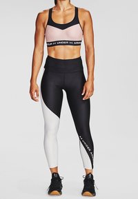 Czarny i różowy sportowy biustonosz z czarnym paskiem; legginsy z wysokim stanem w czarno-białym kolorze z asymetrycznym wzorem; teksturowana tkanina, dopasowany krój.