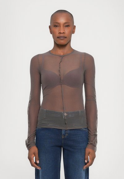 Top lungo trasparente in marrone, con chiusura frontale a bottoni, tessuto texturizzato e un corpetto aderente con un design a strati sopra un reggiseno.