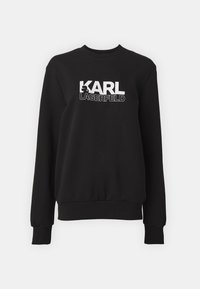 Čierna mikina vyrobená z mäkkej tkaniny, s okrúhlym výstrihom a dlhými rukávmi. Na prednej strane je biela text "KARL LAGERFELD."