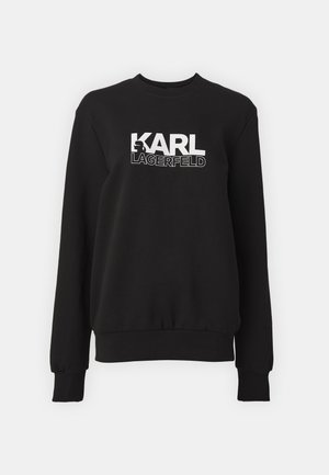 Musta dressipluus pehmest kangast, millel on ümar kaelus ja pikad varrukad. Ees on valge tekst "KARL LAGERFELD."