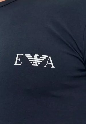 Marineblå bomulds t-shirt med et hvidt logo, der har stiliserede vinger og bogstaverne "EVA" trykt på brystet. Klassisk pasform, korte ærmer.