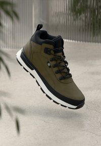 Olivzaļš augstie sporta apavi ar melniem akcentiem, teksturētu virsu, apaļām šņorēm un baltu zolīti. Viegls dizains ar izteiktām šuvju detaļām.