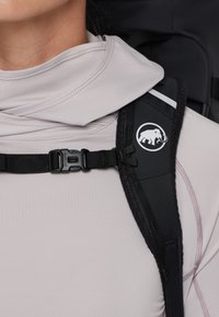 Svart selebånd med justerbar spenne, med en hvit logo av en elefant. Mykt, lysegrått stoff synlig under.