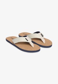 Infradito in sughero con una fascia in tessuto beige. La suola è blu e il design presenta un profilo piatto con accenti minimi.