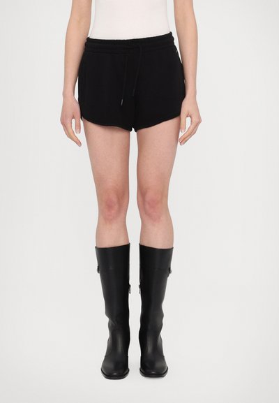 Sorte svedshorts med elastisk talje og snøre, med sidelommer og buet søm, parret med knævare sorte støvler.