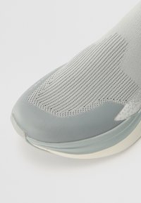 Hallitus hallitusking, millel on hingav võrkmaterjalist ülakeha, sujuv ümar varvas ja tekstuuriga kudumine, mida täiendab pehme kummist tald.