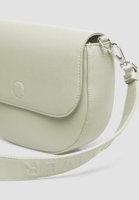 Lichtgroene leren crossbodytas met een gebogen vorm, een klepopening en een gestructureerde afwerking. De schouderband heeft reliëfletters.