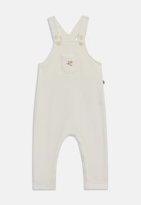 Kremfarget jumpsuit laget av myk stoff, med justerbare stropper, to knapper og en dekorativ lomme med blomsterbroderi.