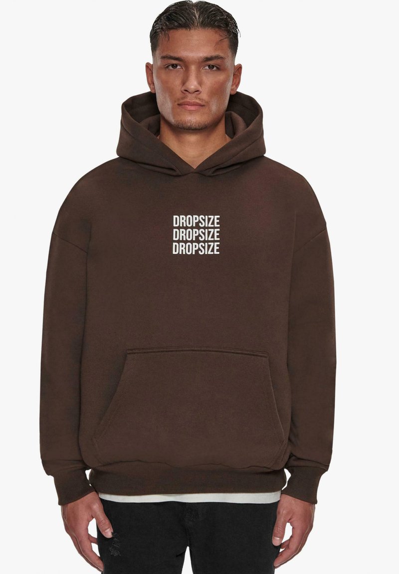 Brauner Kapuzenpullover aus weichem Stoff mit einer vorderen Tasche und Bündchenärmeln. "DROPSIZE" mehrfach in Weiß auf der Vorderseite aufgedruckt.