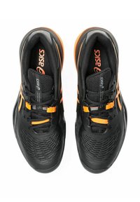 Zapatillas deportivas negras con acentos naranjas, que presentan un diseño elegante, una parte superior texturizada y cordones y logotipo de alta visibilidad en contraste.