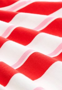 Cotton fabric with bold red and soft pink waves, alternating with white stripes. Smooth texture, vibrant color contrast.