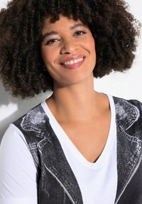 Camiseta blanca con un diseño gráfico negro de una chaqueta de mezclilla. Cuello en V y mangas cortas, con una textura de algodón suave.