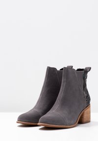 Botines de ante gris con un panel trasero texturizado y un tacón de madera en capas. Presenta una punta redondeada e inserciones laterales elásticas.