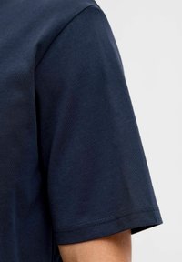 Navyblauwe t-shirt met korte mouwen van zacht katoen. Heeft een ronde halslijn en een gladde textuur met nette stiksels op de mouwen.