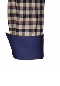 Camicia a quadri con un motivo beige e marrone, con polsini blu scuro. Il tessuto appare liscio con una finitura leggermente strutturata.