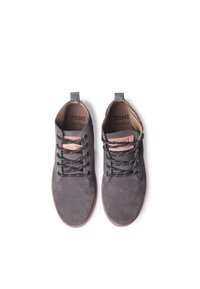 Las botas de tobillo de ante gris tienen una superficie texturizada, cordones en contraste en negro y blanco, y una etiqueta rosa en la lengüeta, con un diseño de punta redondeada.