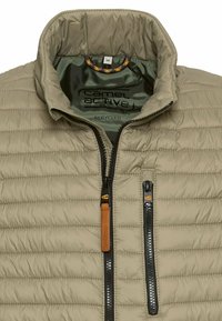 Leichte Jacke aus recyceltem Stoff in Beige mit einem Reißverschluss vorne, horizontaler Steppung und einem inneren kontrastierenden grünen Futter.