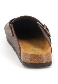 Il mocassino in pelle marrone presenta un'ampia apertura, una soletta in sughero testurizzato e un'aggiunta di fibbia metallica sul lato. Suola in gomma liscia e piatta.