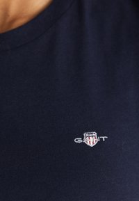 Mørkeblå bomull t-skjorte med rund hals. Har et lite brodert logo i hvitt og rødt på venstre bryst.