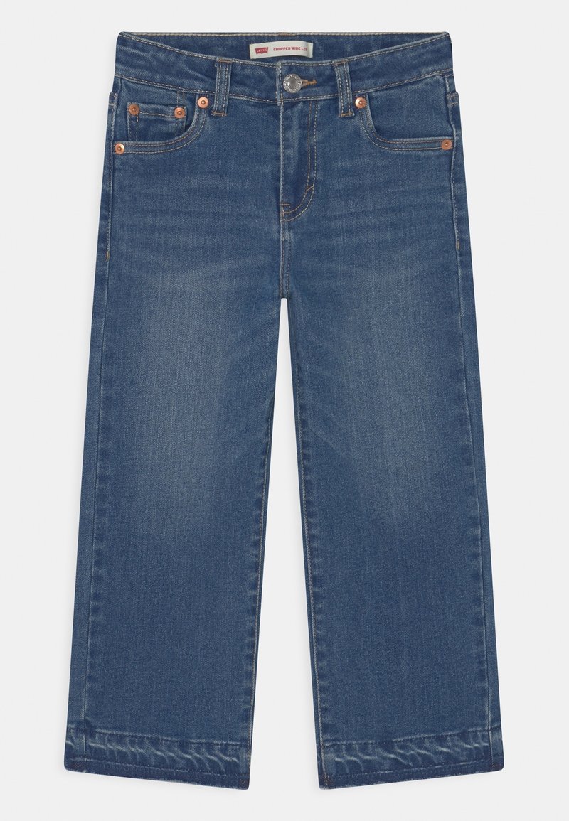 Jean denim bleu moyen cropped à jambes larges, cinq poches, fermeture à boutons et détails en rivets cuivre.