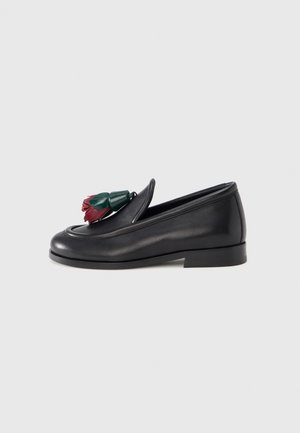 Black leather loafer with a smooth texture, featuring a decorative floral accent in red and green on the upper. Low stacked heel.