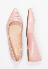 Ballerine in pelle sintetica rosa con punta appuntita, dotate di tre anelli dorati e suole in gomma marrone. L'interno è beige con il logo del marchio.