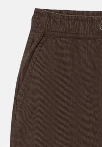 Bruine corduroy broek met een ribbeltextuur, voorzien van een elastische tailleband en zijzakken. De stof is zacht en heeft een lichte glans.