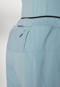 Ανοιχτό μπλε παντελόνι με λεία υφή, διαθέτει ελαστική μέση, πλαϊκή τσέπη με φερμουάρ και διακριτικό λογότυπο.