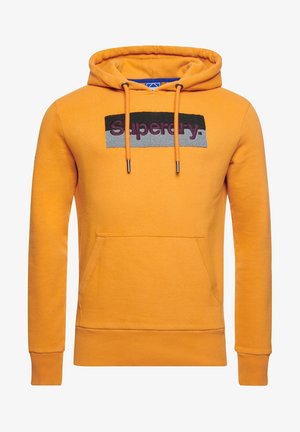 Orangefarbener Kapuzenpullover mit vorderer Kängurutasche und schwarz-grauem Aufnäher, der das Wort "Superdry" in burgunderroten Buchstaben zeigt.