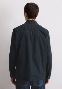 Dunkelblaues Button-up-Hemd aus glattem Stoff, mit klassischem Kragen, langen Ärmeln und Knopfmanschetten, von hinten dargestellt.