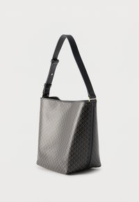 Τσάντα χειρός με μαύρο και γκρι μοτίβο, ρυθμιζόμενο μαύρο δερμάτινο ιμάντα ώμου και εξαρτήματα σε χρυσό τόνο σε λευκό φόντο.