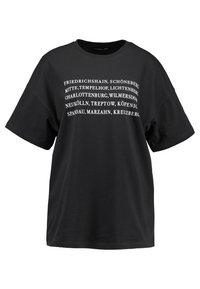 Camiseta de gran tamaño negra hecha de algodón con texto blanco que enumera los barrios de Berlín en una fuente sans-serif en negrita.