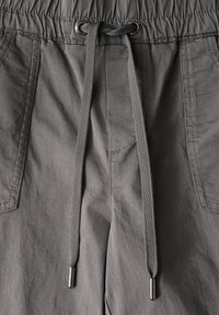 Grijze sportshorts hebben een elastische tailleband met een trekkoord, twee zijzakken en een lichte, gladde stofstructuur.