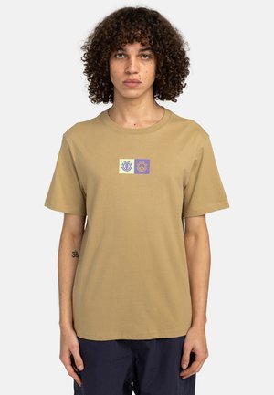 Lys brun bomulds T-shirt med rund hals og korte ærmer. Har et lille grafik i grøn og lilla centreret på brystet.