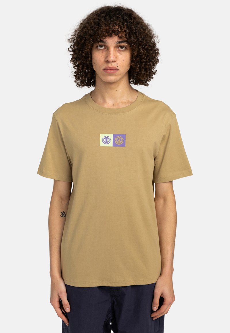 Beige Baumwoll-T-Shirt mit Rundhalsausschnitt und kurzen Ärmeln. Es hat ein kleines grafisches Motiv in Grün und Lila, das auf der Brust zentriert ist.