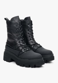 Zwarte leren veterschoenen met een stevige rubberen zool en een gladde afwerking. Enkelhoog ontwerp met een slanke silhouet en geen zichtbare merkvermelding.