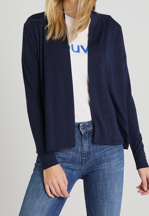 Marinblå öppen fram kardiagan gjord av ett mjukt tyg, med långa ärmar och en avslappnad passform, lager över en vit t-shirt med blå text.