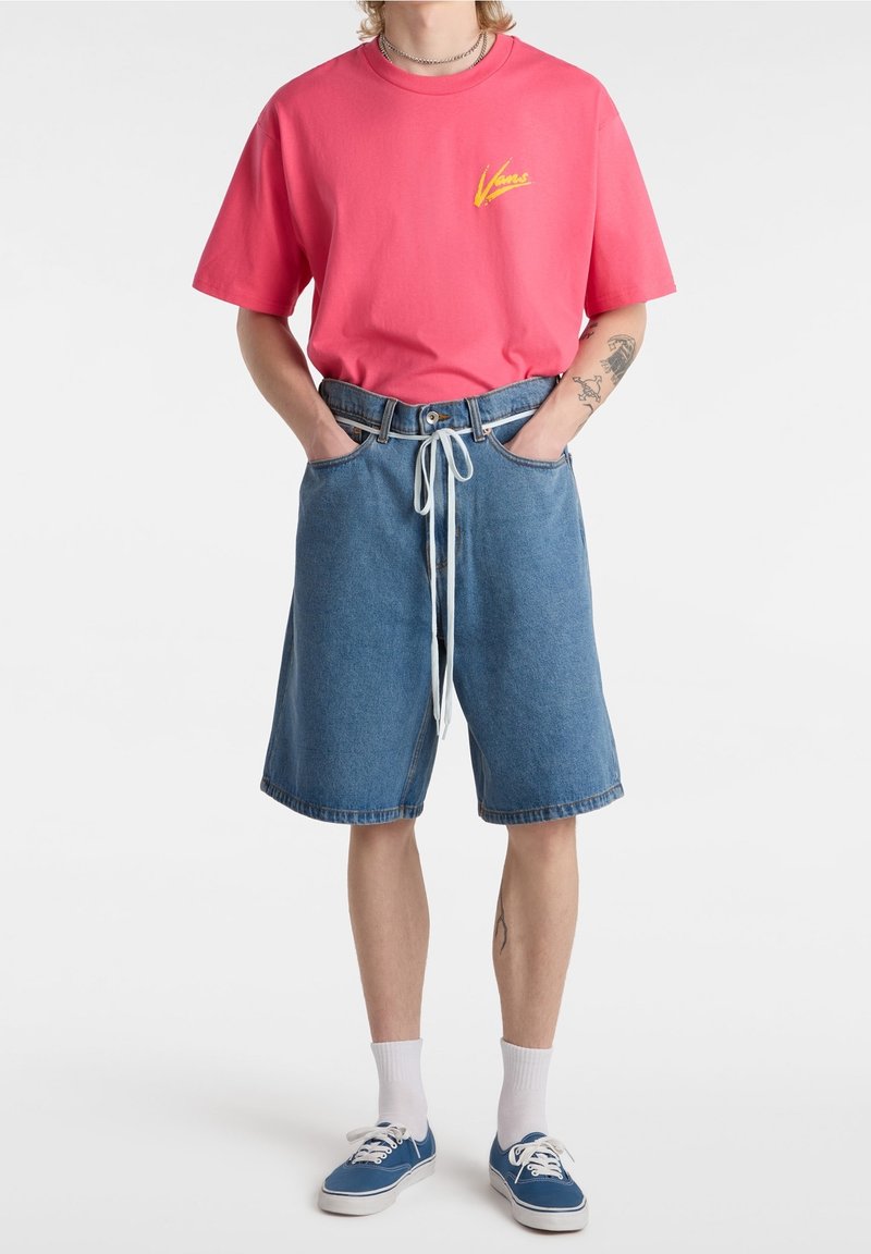 Pink cotton t-shirt with a yellow logo, paired with loose blue denim shorts featuring an adjustable drawstring and cuffed hem.