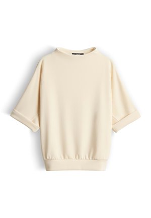 Top a maniche corte color crema con risvolti, scollatura rotonda e orlo elastico, mostrato su sfondo bianco.
