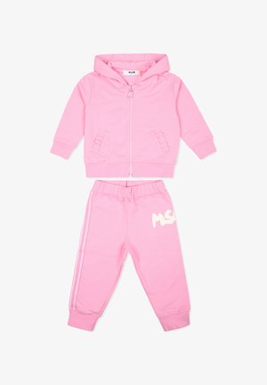 Felpa rosa con zip anteriore, due tasche laterali e polsini a costine. I pantaloni joggers rosa coordinati presentano una vita elasticizzata e un dettaglio con logo bianco.
