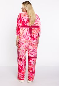 Bloemmotief, roze en koraalkleurige twee-delige outfit; lose top met 3/4 mouwen, bijpassende wijde broek met gestreepte accenten.
