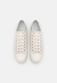 Baskets en cuir blanc avec une texture lisse, six paires d'œillets et un bout arrondi. Design minimaliste avec des détails de couture subtils.
