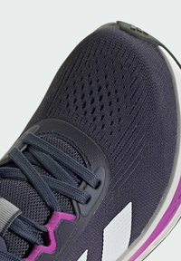 Scarpa da corsa da uomo con tomaia in mesh blu scuro testurizzato, accenti grigi, dettagli lavanda e logo bianco. Presenta lacci e aree forate.