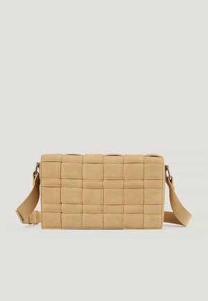 Beige rechthoekige crossbodytas met brede, gevlochten, gewatteerde riemen en een verstelbare schouderriem tegen een effen achtergrond.