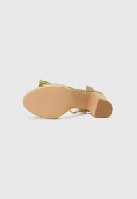Grønn satin heeled sandal med avrundet tå, ankelrem og lys brun teksturert såle. Har en kraftig hæl for stabilitet.