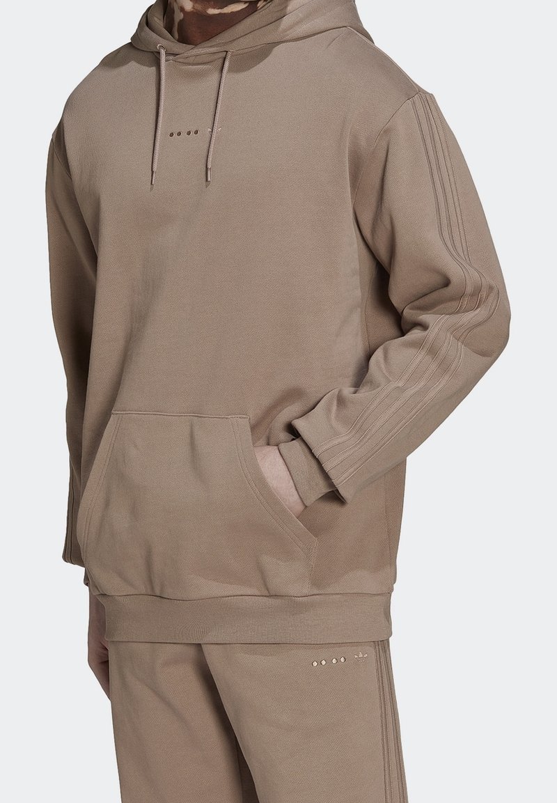 Beige hoodie i mjukt material med framficka, huva med dragsko och tre vertikala ränder på varje ärm.