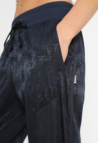 Námořnické sportovní kalhoty vyrobené z texturované tkaniny mají jemný vzor, elastický pas s tkaničkou, boční kapsy a vyšívané logo.